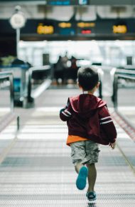 Un bambino corre verso un terminal dell'aeroporto su un nastro trasportatore