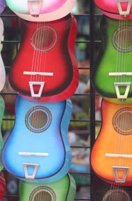 Diversi ukulele colorati appesi a una griglia di ferro
